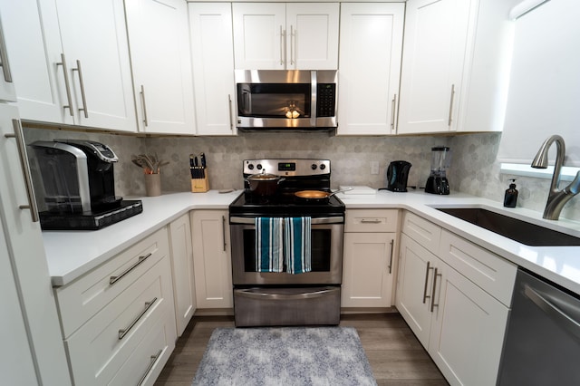 kitchen featuring stainless steel appliances, a sink, white cabinets, and light countertops