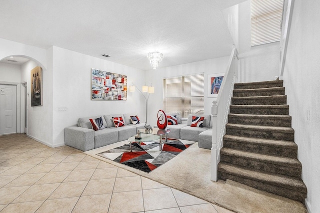 tiled living area featuring arched walkways, stairway, and baseboards