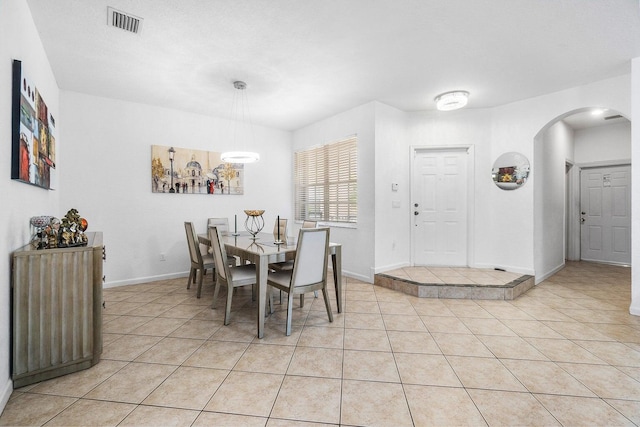 dining room with arched walkways, light tile patterned flooring, and baseboards