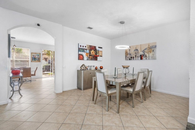 dining area with arched walkways, light tile patterned floors, and baseboards