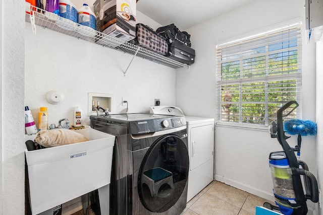 clothes washing area featuring independent washer and dryer, light tile patterned flooring, and baseboards