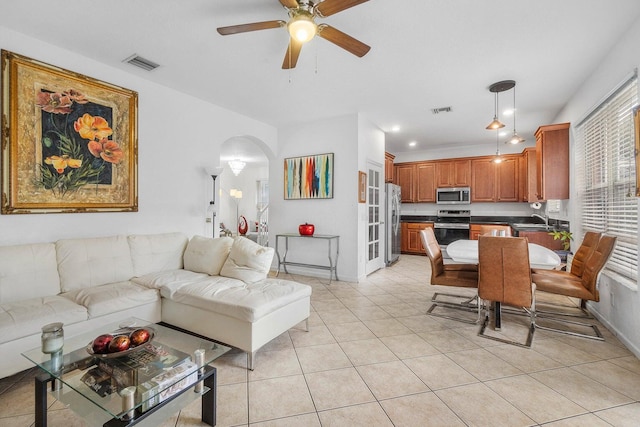 living area featuring arched walkways, a ceiling fan, light tile patterned floors, baseboards, and recessed lighting