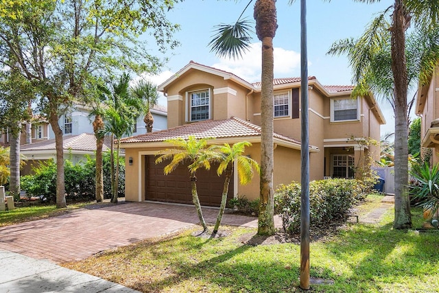 mediterranean / spanish-style house featuring stucco siding, decorative driveway, a tiled roof, and a front lawn