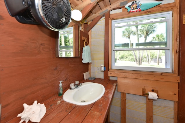 1116 NE Oceanview Cir, Jensen Beach, FL 34957 - bathroom featuring healthy amount of natural light, wooden walls, vanity, and vaulted ceiling