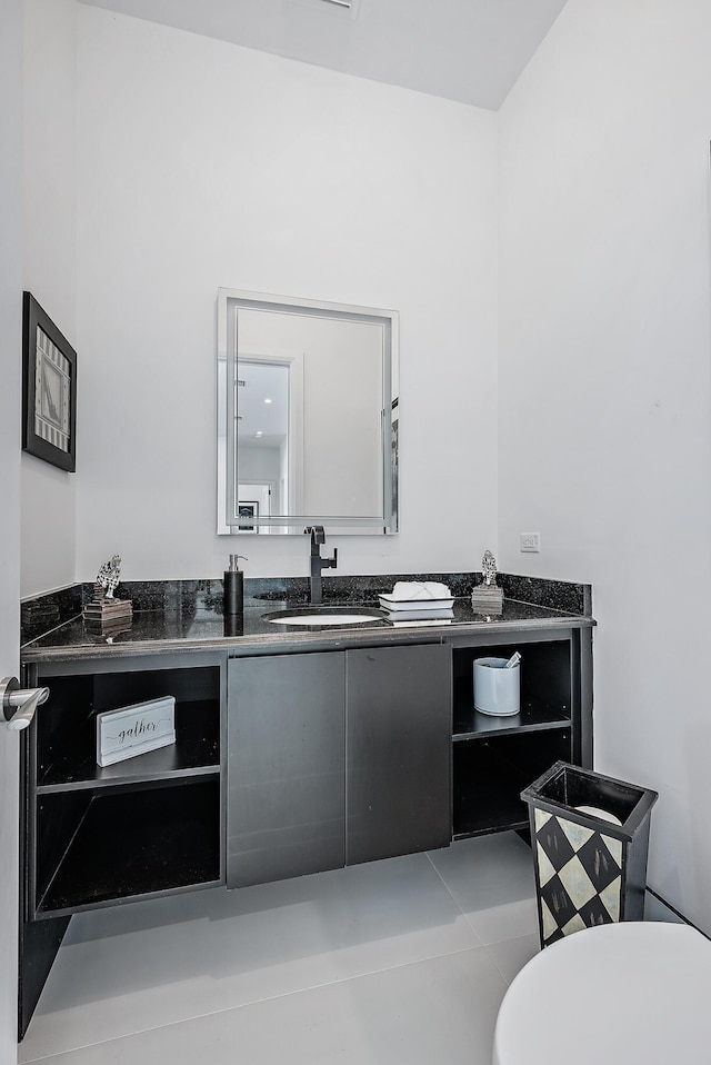 half bathroom with vanity, toilet, and tile patterned flooring