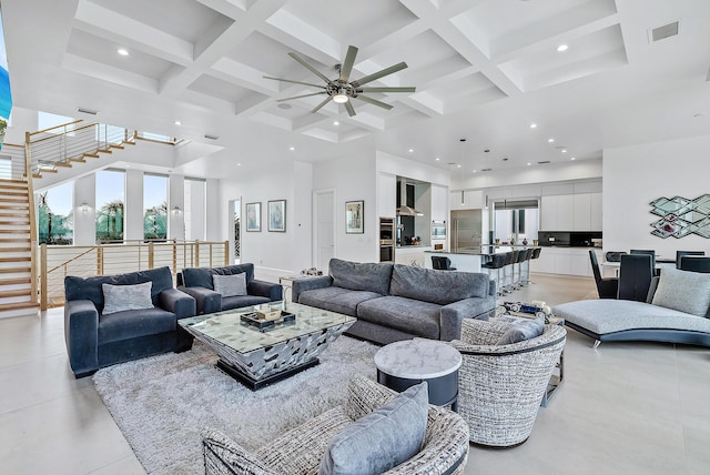 living area with a towering ceiling, coffered ceiling, recessed lighting, a ceiling fan, and beamed ceiling