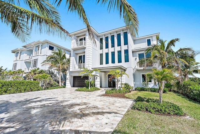 view of front of home featuring stucco siding, a garage, decorative driveway, and a balcony