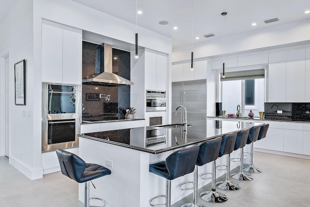 kitchen featuring modern cabinets, wall chimney range hood, stainless steel appliances, a sink, and recessed lighting