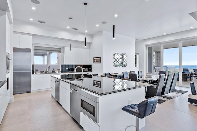 kitchen with modern cabinets, a sink, dark countertops, stainless steel appliances, and recessed lighting