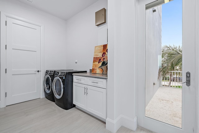 washroom with light wood-style flooring, washing machine and dryer, and cabinet space