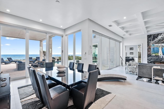 dining space with recessed lighting, coffered ceiling, beamed ceiling, a water view, and concrete flooring