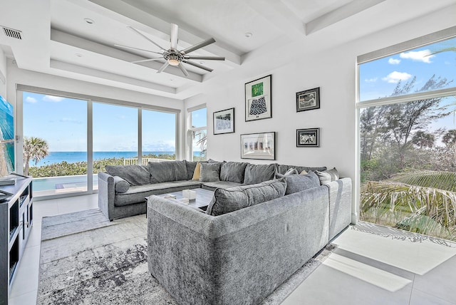 living room featuring a water view, a ceiling fan, plenty of natural light, and beamed ceiling