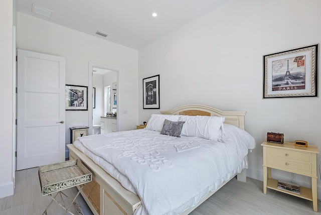 bedroom with light wood-type flooring, ensuite bathroom, and recessed lighting