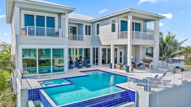 rear view of property featuring a balcony, a patio area, metal roof, and a pool with connected hot tub