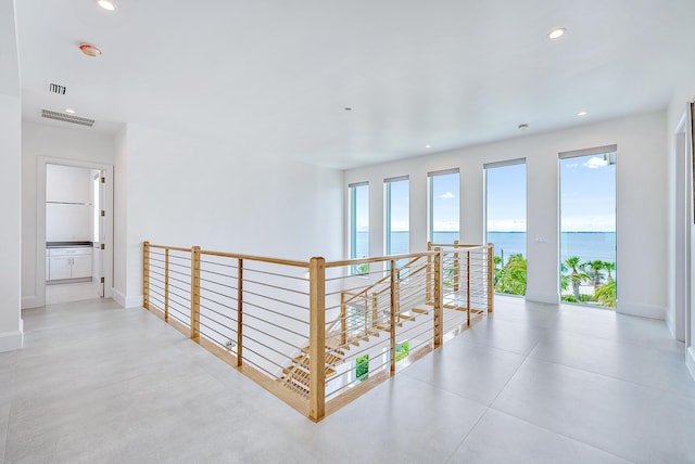 hall with an upstairs landing, recessed lighting, a water view, and baseboards