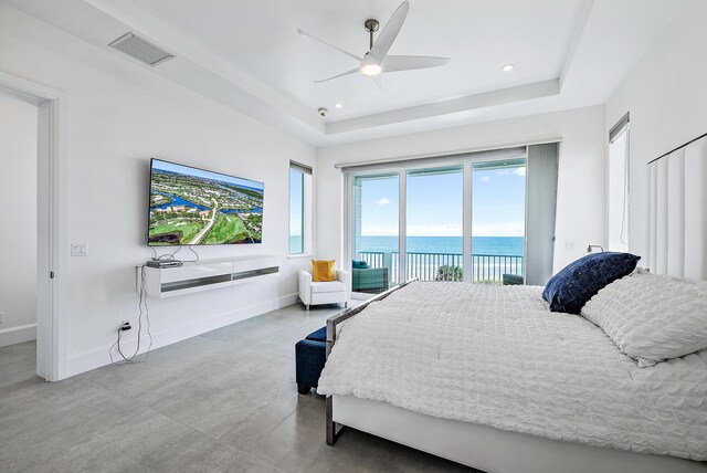 bedroom featuring access to outside, a tray ceiling, concrete flooring, baseboards, and recessed lighting