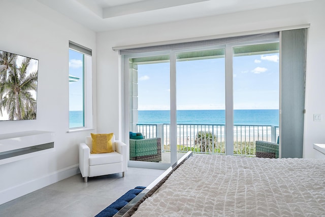 bedroom featuring multiple windows, a water view, access to exterior, and baseboards