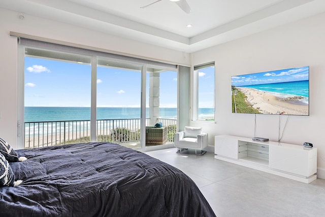 bedroom with concrete floors, access to exterior, view of water and beach, baseboards, and recessed lighting