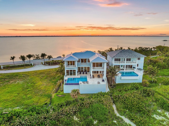 aerial view of property and surrounding area with a pool and a nearby body of water