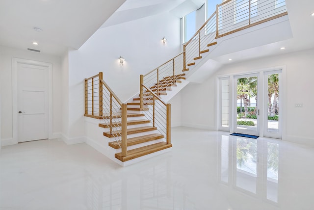 stairway featuring baseboards, a towering ceiling, recessed lighting, and tile patterned floors