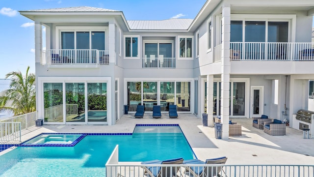 view of swimming pool featuring an outdoor living space, a patio, exterior kitchen, a pool with connected hot tub, and grilling area