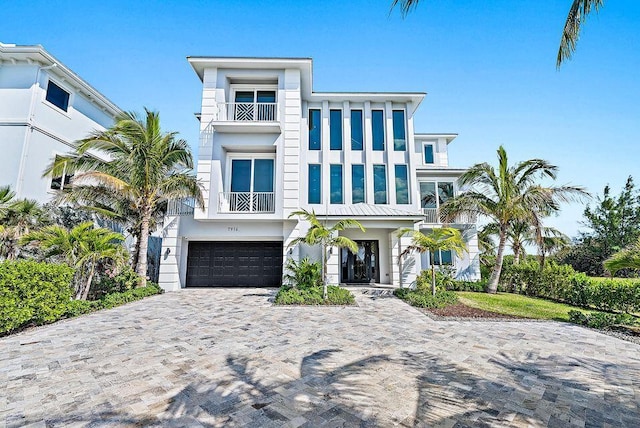 view of front of property with a balcony, an attached garage, stucco siding, and decorative driveway