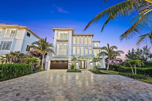 view of front facade with an attached garage, decorative driveway, stucco siding, and a balcony