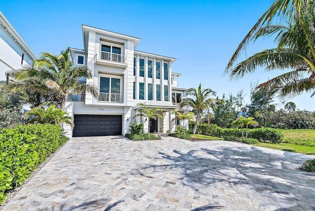 view of front of property with a balcony, an attached garage, decorative driveway, and stucco siding