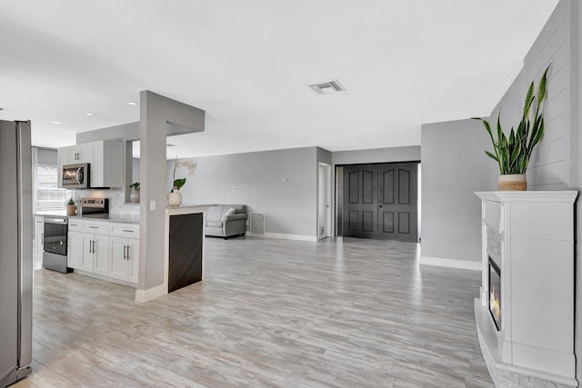 1181 Larch Way, Wellington, FL 33414 - unfurnished living room featuring baseboards, light wood finished floors, and a glass covered fireplace