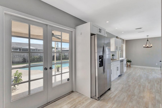 1181 Larch Way, Wellington, FL 33414 - kitchen featuring stainless steel appliances, french doors, white cabinetry, a chandelier, and light wood finished floors