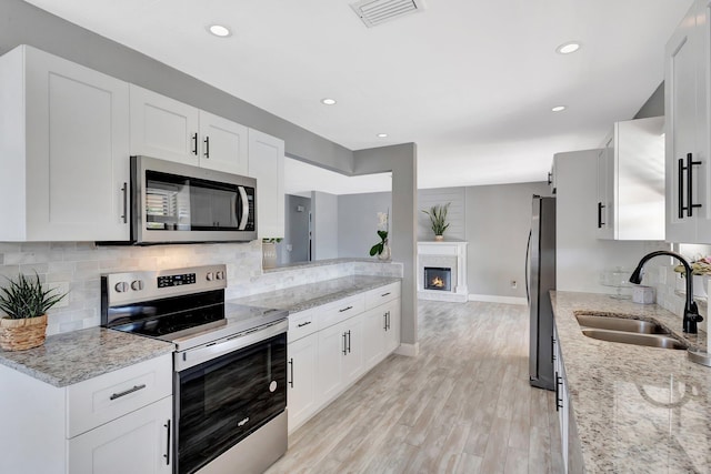 1181 Larch Way, Wellington, FL 33414 - kitchen featuring stainless steel appliances, a sink, decorative backsplash, light wood-type flooring, and baseboards