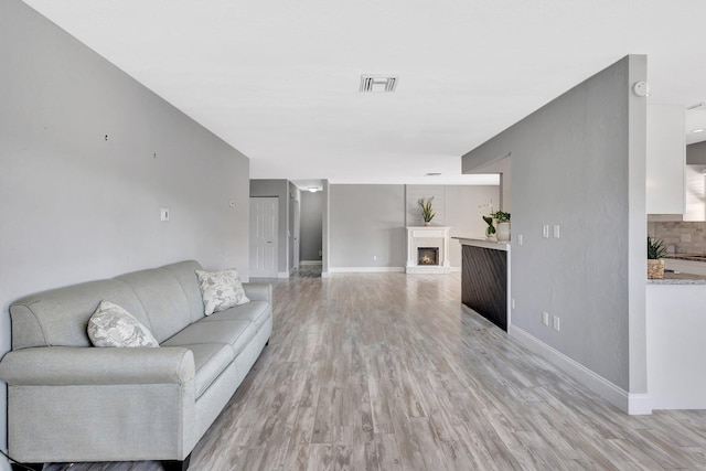 1181 Larch Way, Wellington, FL 33414 - living area featuring a lit fireplace, light wood finished floors, and baseboards
