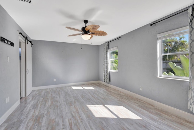 1181 Larch Way, Wellington, FL 33414 - spare room with a barn door, ceiling fan, wood finished floors, and baseboards