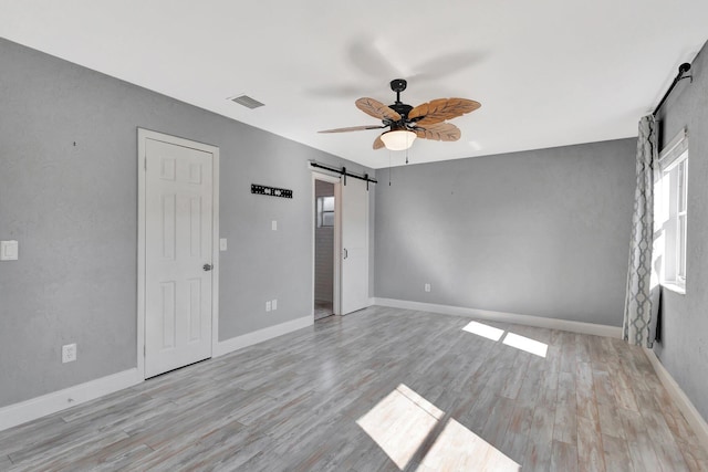 1181 Larch Way, Wellington, FL 33414 - unfurnished bedroom with a barn door, wood finished floors, baseboards, and ceiling fan