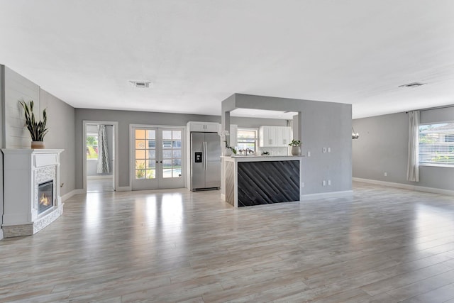 1181 Larch Way, Wellington, FL 33414 - unfurnished living room featuring a glass covered fireplace, light wood-style flooring, and baseboards
