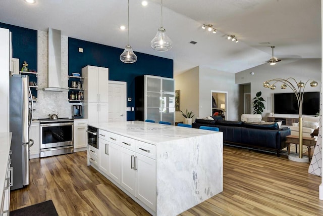 7340 Anadale Cir, Lake Worth, FL 33467 - kitchen with wall chimney exhaust hood, stainless steel appliances, wood finished floors, white cabinetry, and recessed lighting
