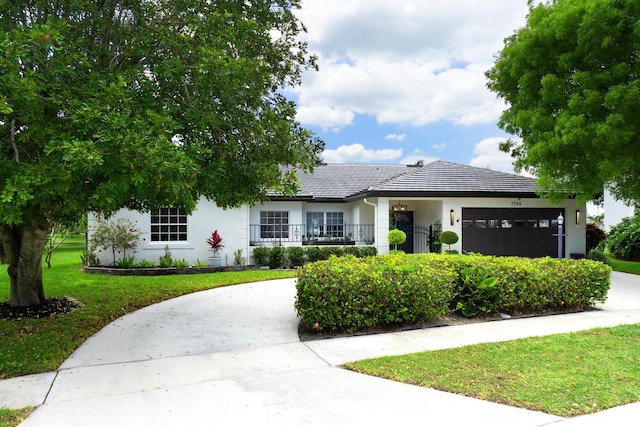 7340 Anadale Cir, Lake Worth, FL 33467 - view of front of home with curved driveway, stucco siding, a front yard, a garage, and a tiled roof