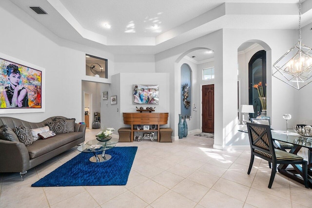 living area featuring light tile patterned floors, a high ceiling, arched walkways, and a raised ceiling