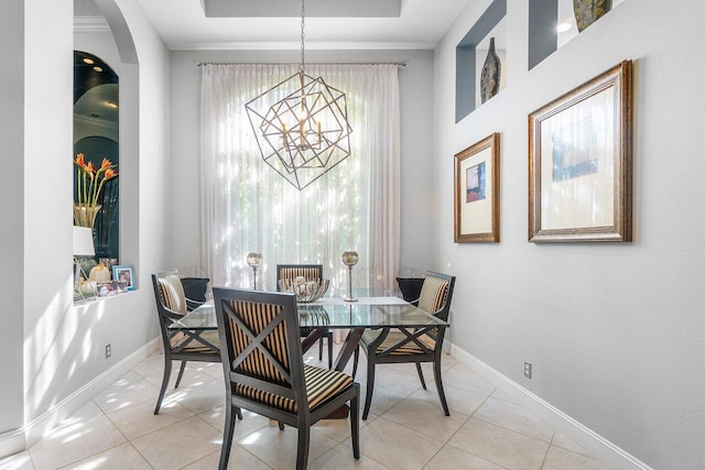 dining area with light tile patterned flooring, a tray ceiling, a chandelier, and baseboards