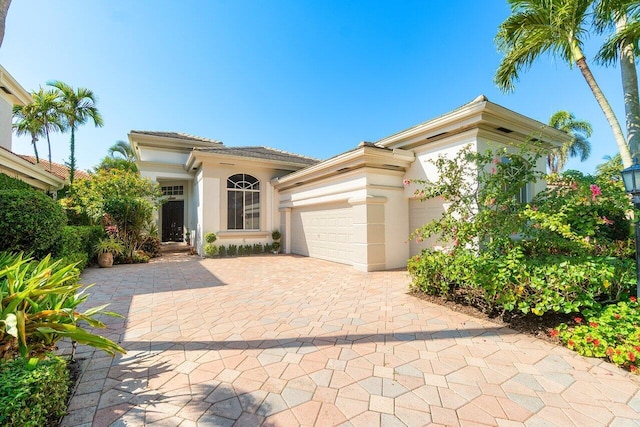 mediterranean / spanish-style home featuring stucco siding, an attached garage, decorative driveway, and a tiled roof