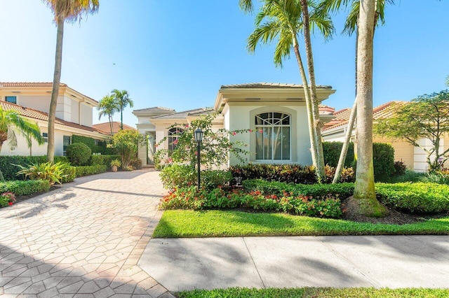 mediterranean / spanish-style house with stucco siding, a tile roof, and decorative driveway