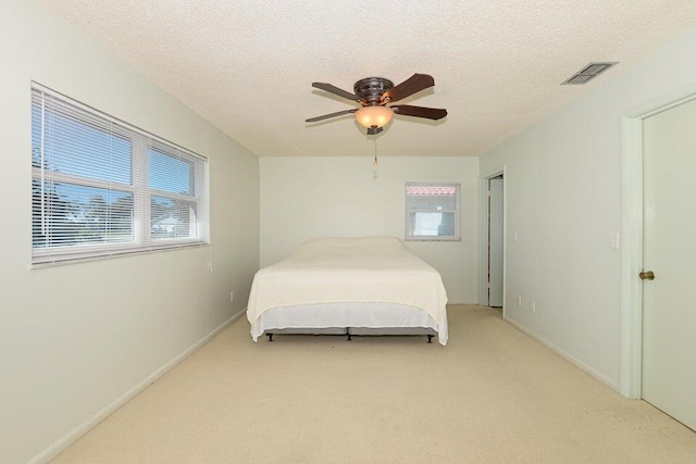 1117 SE Mendoza Ave, Port Saint Lucie, FL 34952 - bedroom with multiple windows, light colored carpet, a ceiling fan, a textured ceiling, and baseboards