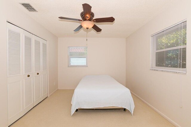 1117 SE Mendoza Ave, Port Saint Lucie, FL 34952 - bedroom featuring a closet, light carpet, a ceiling fan, baseboards, and a textured ceiling