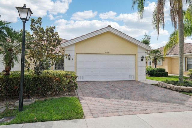 10853 SW Elsinore Dr, Port Saint Lucie, FL 34987 - view of front facade with stucco siding, decorative driveway, and an attached garage