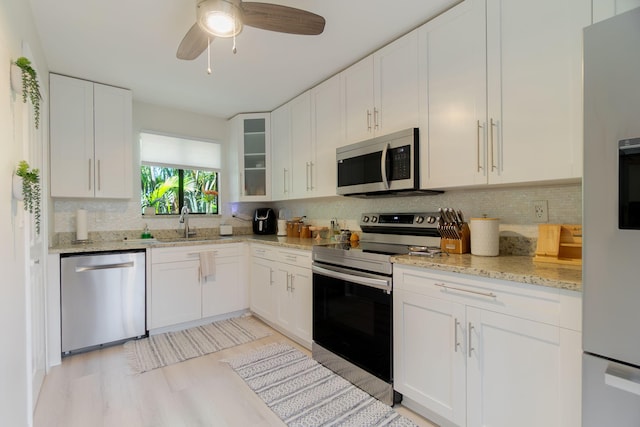 11892 Sturbridge Ln, Wellington, FL 33414 - kitchen featuring appliances with stainless steel finishes, tasteful backsplash, glass insert cabinets, and light wood-type flooring