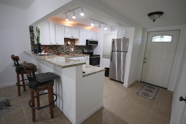 9842 Marina Blvd Unit 711, Boca Raton, FL 33428 - kitchen featuring stainless steel appliances, a peninsula, white cabinetry, light stone countertops, and tasteful backsplash