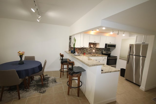 9842 Marina Blvd Unit 711, Boca Raton, FL 33428 - kitchen featuring stainless steel appliances, rail lighting, a peninsula, light tile patterned flooring, and lofted ceiling