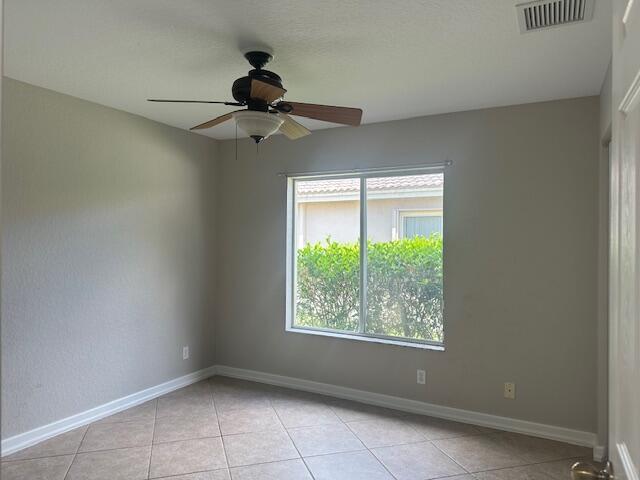 spare room featuring light tile patterned floors, ceiling fan, and baseboards