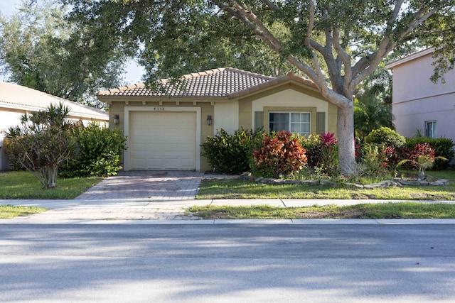 view of front of home featuring a tiled roof, a garage, driveway, and stucco siding