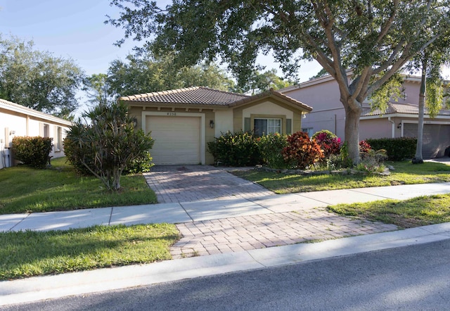 view of front of property featuring a tiled roof, stucco siding, decorative driveway, and an attached garage